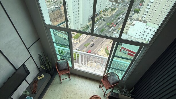 A high-rise apartment with a large window overlooking a cityscape and a body of water. - Beira Mar Ocean-View Loft — Steps from Meireles & Iracema Beach (Fortaleza)
