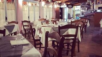 Un ristorante con travi in legno, tavoli con tovaglie bianche e sedie.