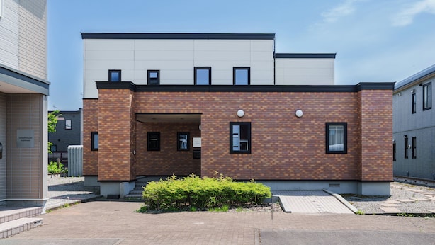Un bâtiment moderne avec une façade en briques, un toit plat et une petite entrée.