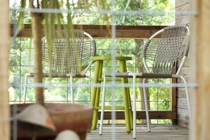 A wooden deck with wicker chairs and a small table, overlooking a lush green landscape. - “The Loft on New Natchitoches” (West Monroe)