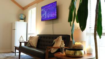 A living room with a sofa, a television, a globe, a lamp, and a table with decorative items.