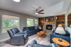 Ein Wohnzimmer mit Kamin, Ledermöbeln und Deckenventilator.