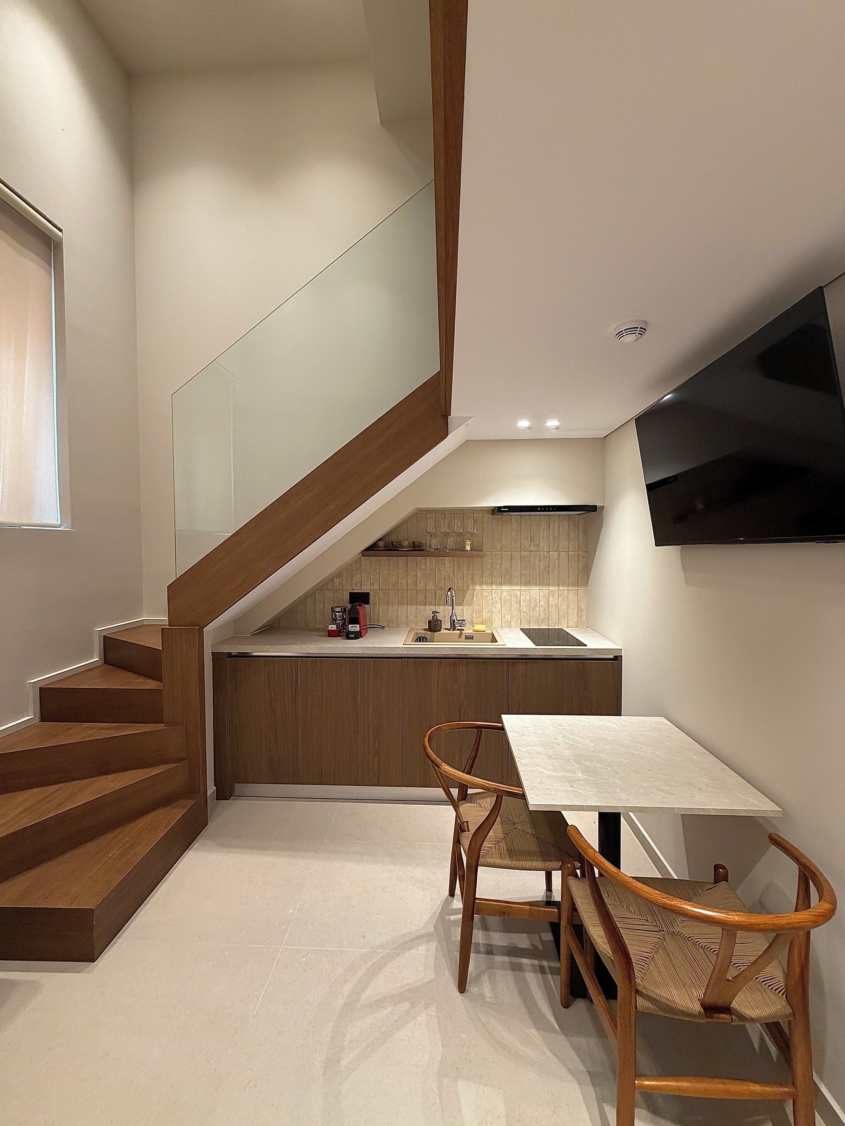 A modern kitchen with a built-in stove, a dining area with a table and chairs, and a staircase leading to an upper level.