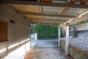 En overdækket veranda med en grussti, der fører til en garage.