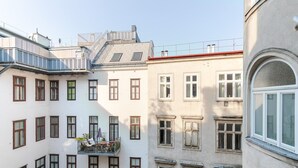 En byggnad med flera våningar, balkonger, ett rött tak och en vit fasad.