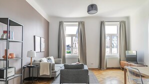 Ett modernt vardagsrum med en soffa, en tv, en bokhylla och en matplats.