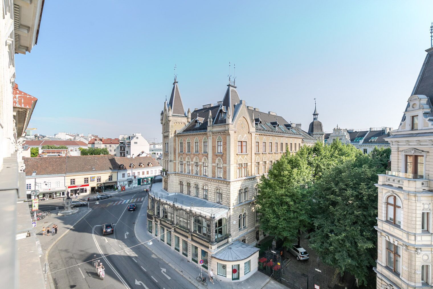 A historic building with a prominent tower, a street with cars, and a pedestrian crossing.