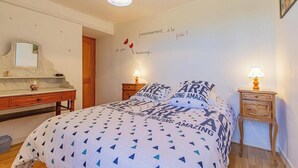 Un dormitorio con cama, mesitas de noche, cómoda y una pared con texto inspirador.