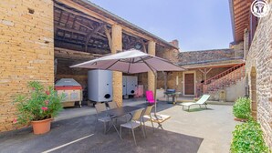 Un patio al aire libre con una mesa, sillas y una parrilla.