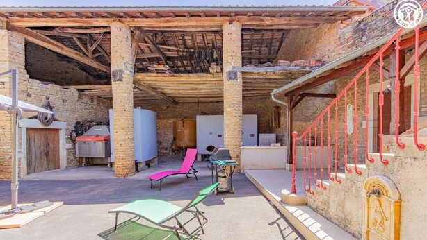 Un espacio al aire libre techado con paredes de piedra, una escalera roja y asientos exteriores.