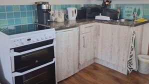 A kitchen with a stove, oven, and countertop with various appliances and items.