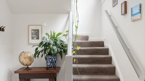 Una escala amb trams aveludats, un glob dins d'una taula de fusta, una planta en test i un quadre a la paret.