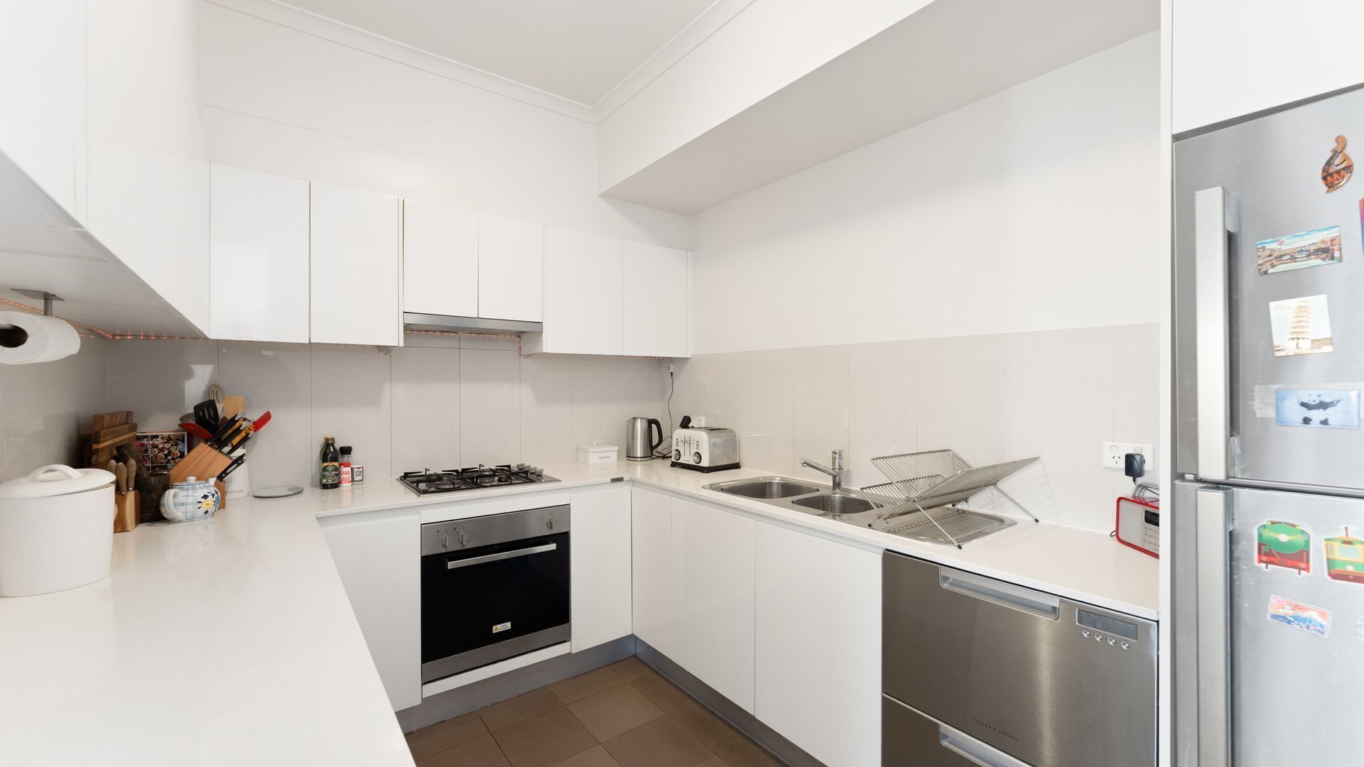 A modern kitchen with white cabinets, stainless steel appliances, and a dishwasher.