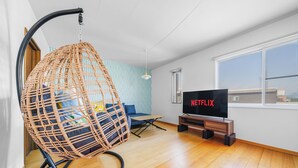 Una sala de estar con un sillón colgante, un sofá, un televisor y una ventana.