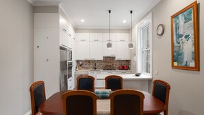Eine moderne Küche mit weißen Schränken, einer Ziegelrückwand und einem Essbereich mit Holztisch und Stühlen.
