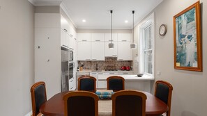 Eine moderne Küche mit weißen Schränken, einer Ziegelrückwand und einem Essbereich mit Holztisch und Stühlen.