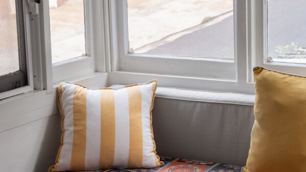 Un siège de fenêtre avec un coussin et vue sur la rue.