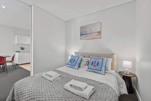 A hotel room with a bed, bedside table, and a painting on the wall. - Central Adelaide 2BR Queen  2 Singles  WiFi (Adelaide)
