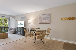 Een moderne woonkamer met een eethoek, een bank, een televisie en een lamp.