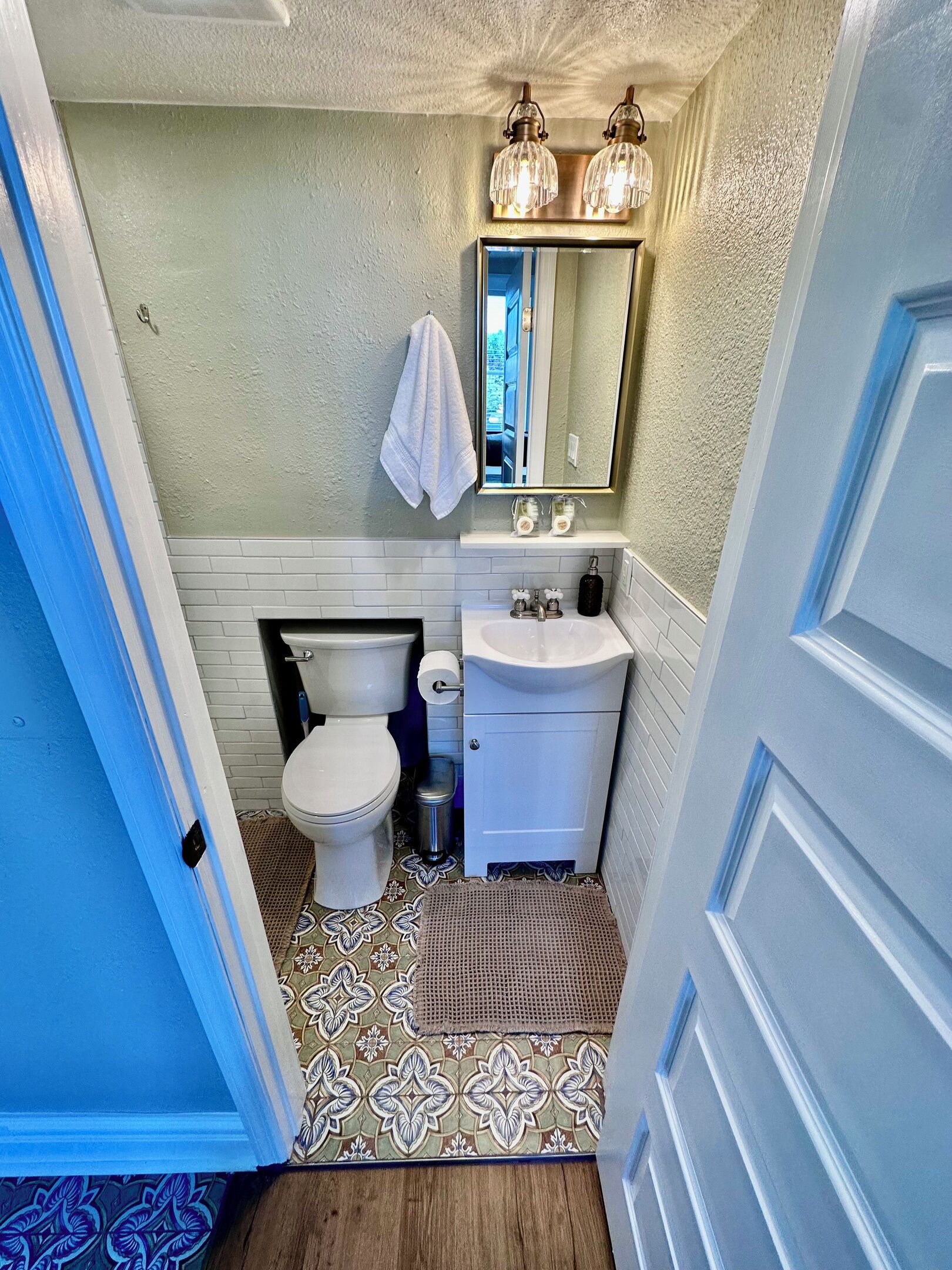 A bathroom with a toilet, sink, and mirror.