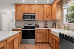 Eine moderne Küche mit Holzschränken, Edelstahlgeräten und einem eingebauten Geschirrspüler.