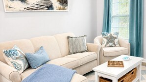 Un soggiorno con un divano color beige, una poltrona abbinata, un tavolino da caffè e un tappeto con motivo geometrico.
