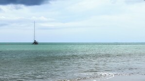 A calm sea with a sailboat and a distant shoreline. - Lujoso Apartamento en la primera linea del mar con picsinas (santiago de tolu)