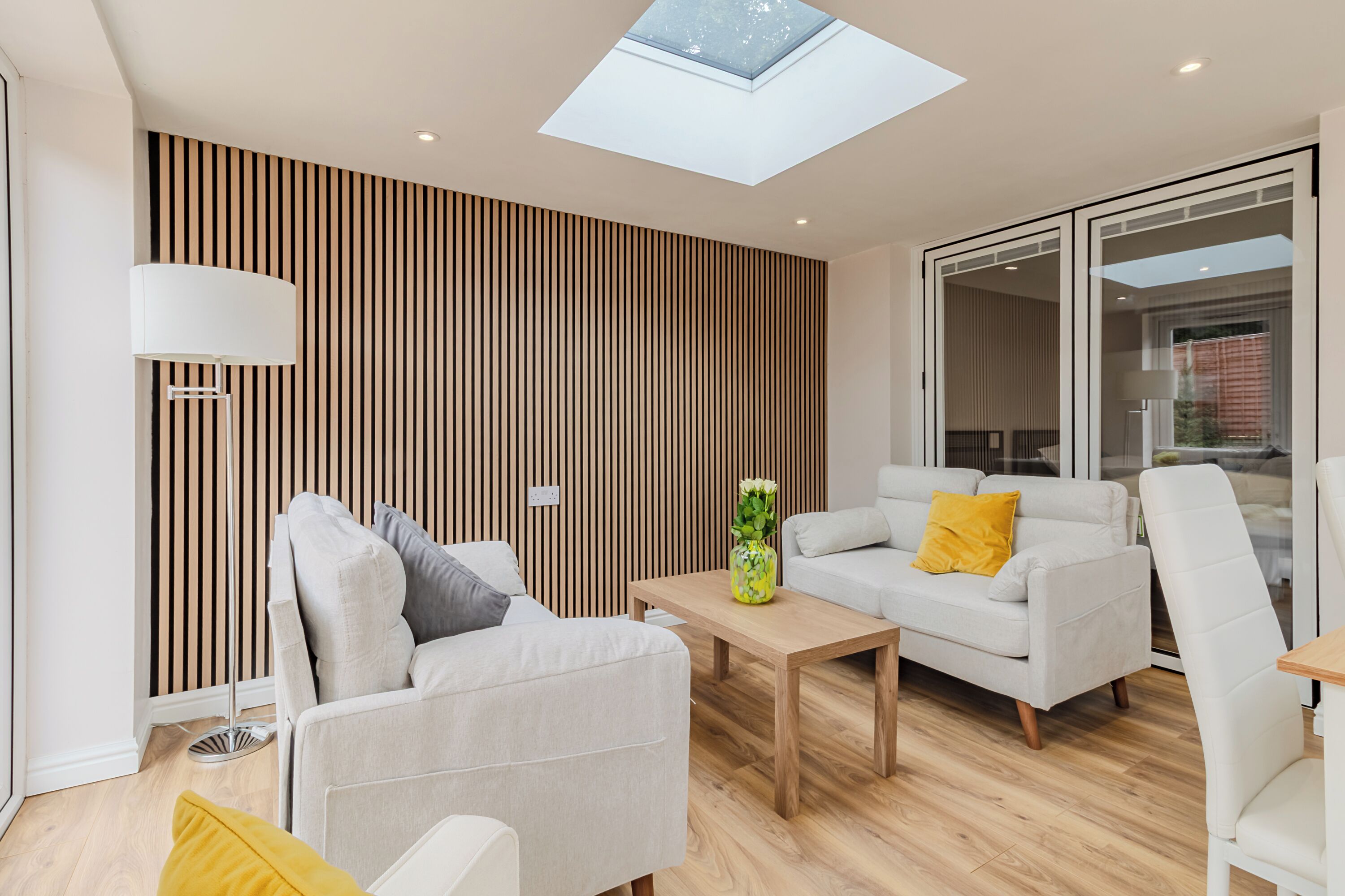 Una sala de estar moderna con tragaluz, un sofá, una mesita de centro y una lámpara.