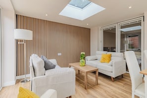 Ein modernes Wohnzimmer mit Oberlicht, einer Couch, einem Couchtisch und einer Lampe.