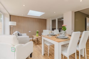 Ein stilvoller Essbereich mit einem Holztisch, weißen Stühlen und einem Blumenstrauß.
