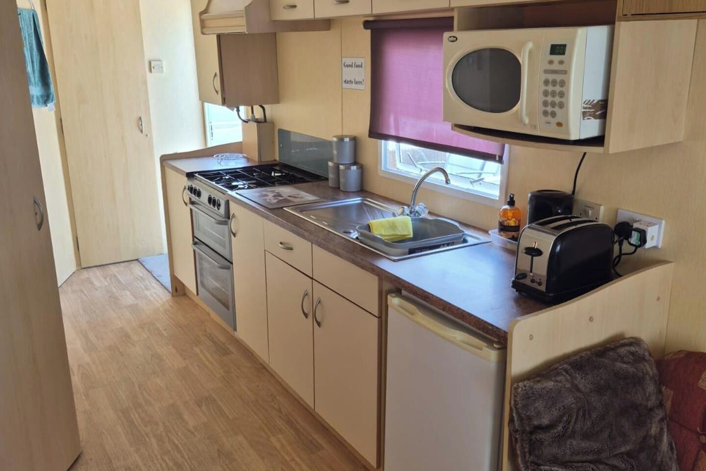 Een kleine keuken met een fornuis, oven, magnetron, spoelbak en broodrooster.