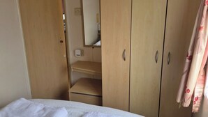 Ein Schlafzimmer mit Bett, Kleiderschrank, Spiegel und Heizkörper.