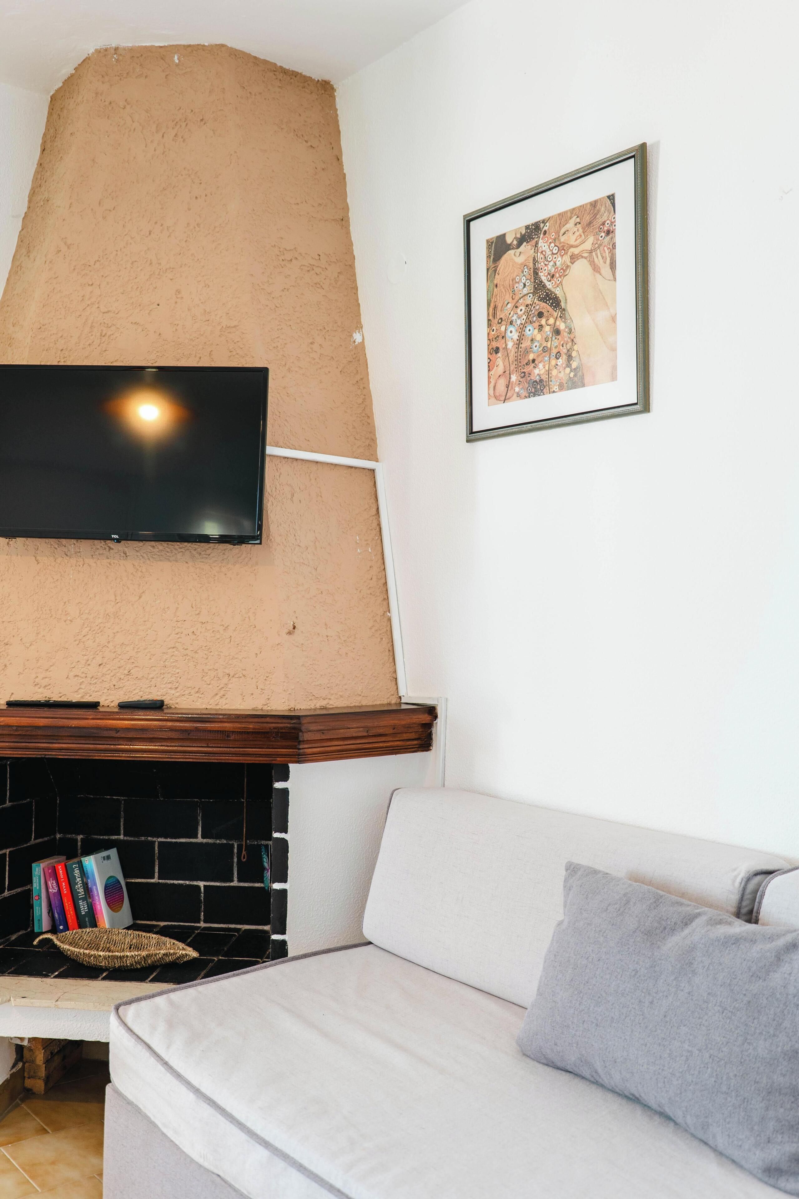 Un salon avec une cheminée, un téléviseur à écran plat, un canapé et un tableau encadré au mur.