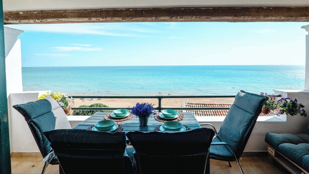 Ein Balkon mit Tisch für zwei Personen, mit Blick auf Strand und Meer.