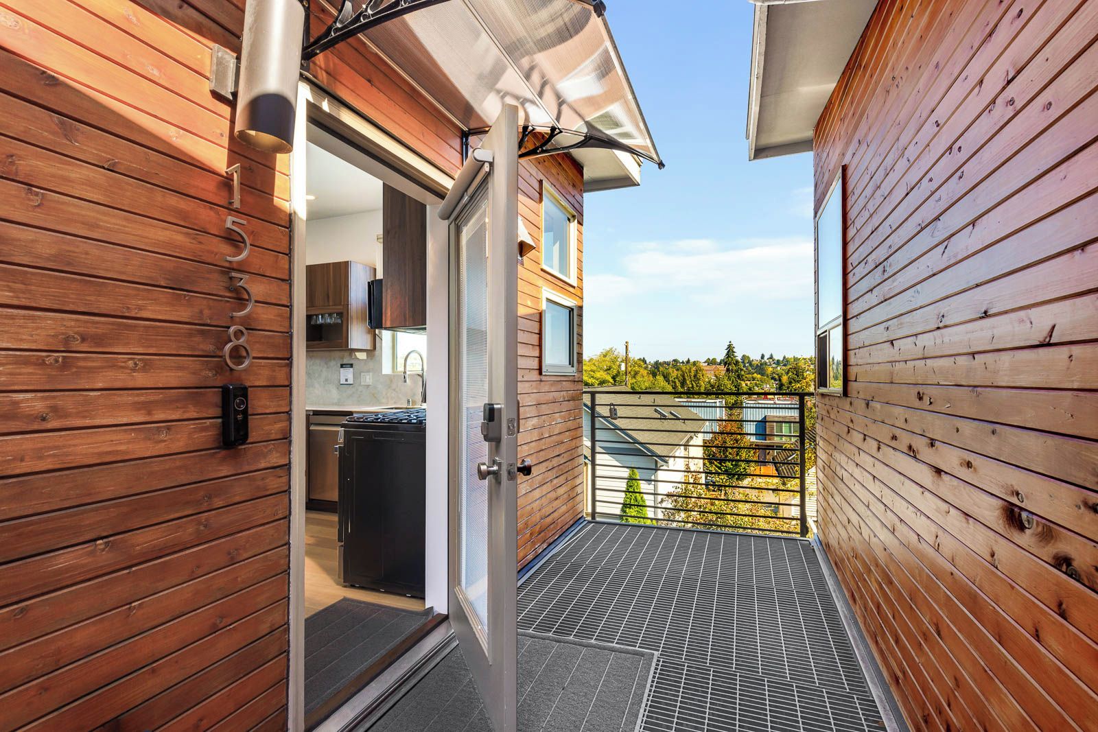 A narrow wooden corridor leading to a modern kitchen with a sliding door.