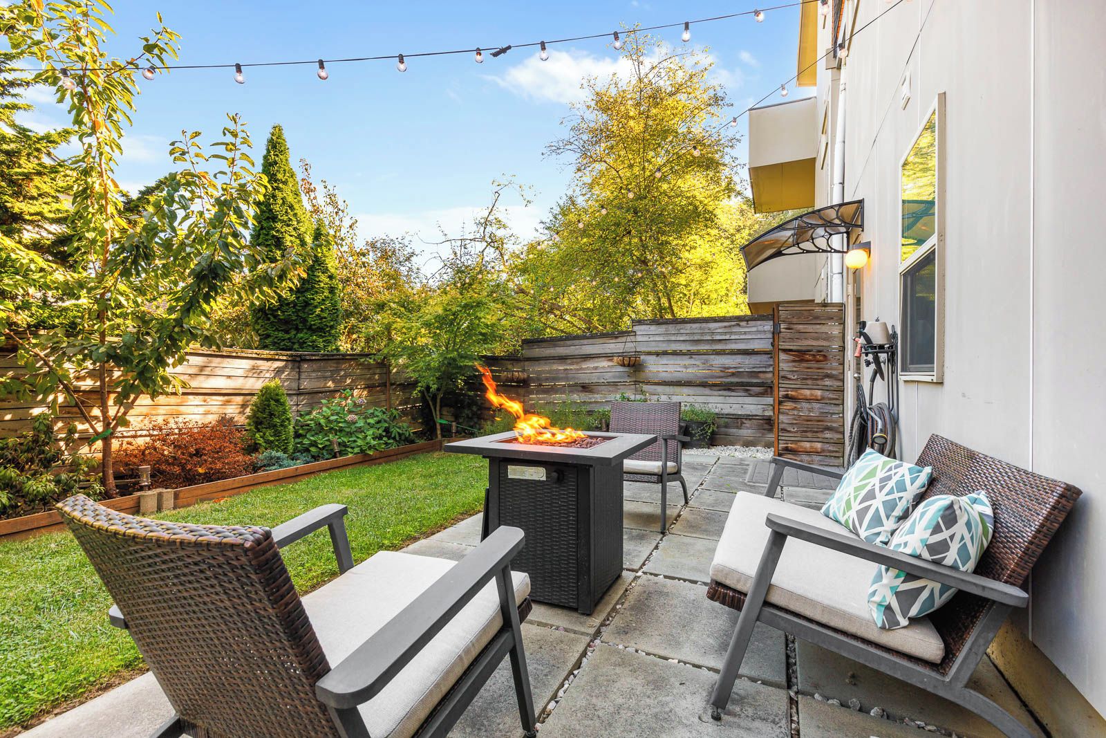 An outdoor patio with a fire feature, seating, and a wooden fence.