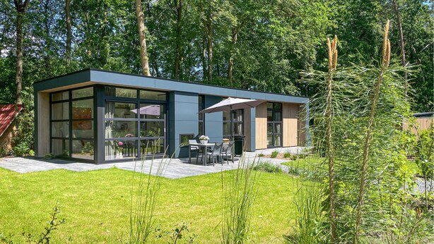 Ein modernes Haus mit Terrasse, Esstisch und Stühlen.