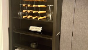 Tumma puinen kirjahylly, jossa on kello, kehystettyjä valokuvia, viinilaseja ja säilytyslaatikoita.