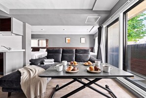 A modern living room with a sofa, coffee table, and a view of greenery outside. - NOBLE 201 (Sapporoshi)