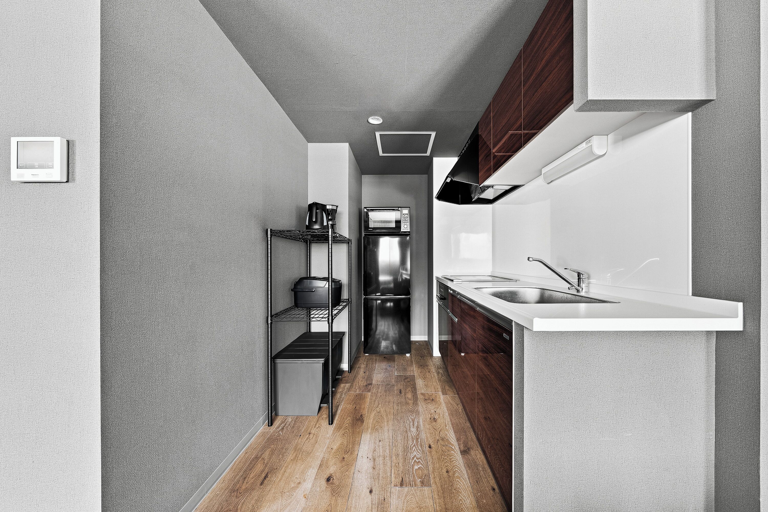 A modern kitchen with a stainless steel refrigerator, a built-in oven, and a wooden floor.