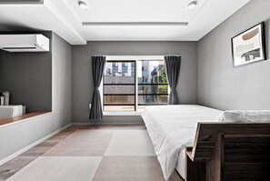 A modern bedroom with a large window, a bed, a bedside table, and a wall-mounted air conditioning unit. - NOBLE 201 (Sapporoshi)