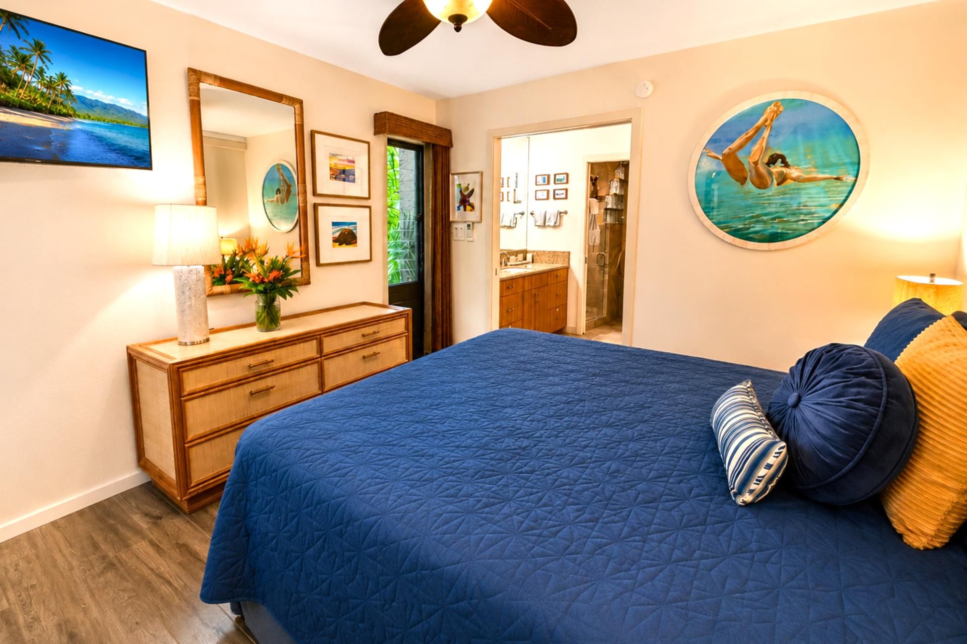 Een slaapkamer met een groot bed, een dressoir, een spiegel en een douchehoek.