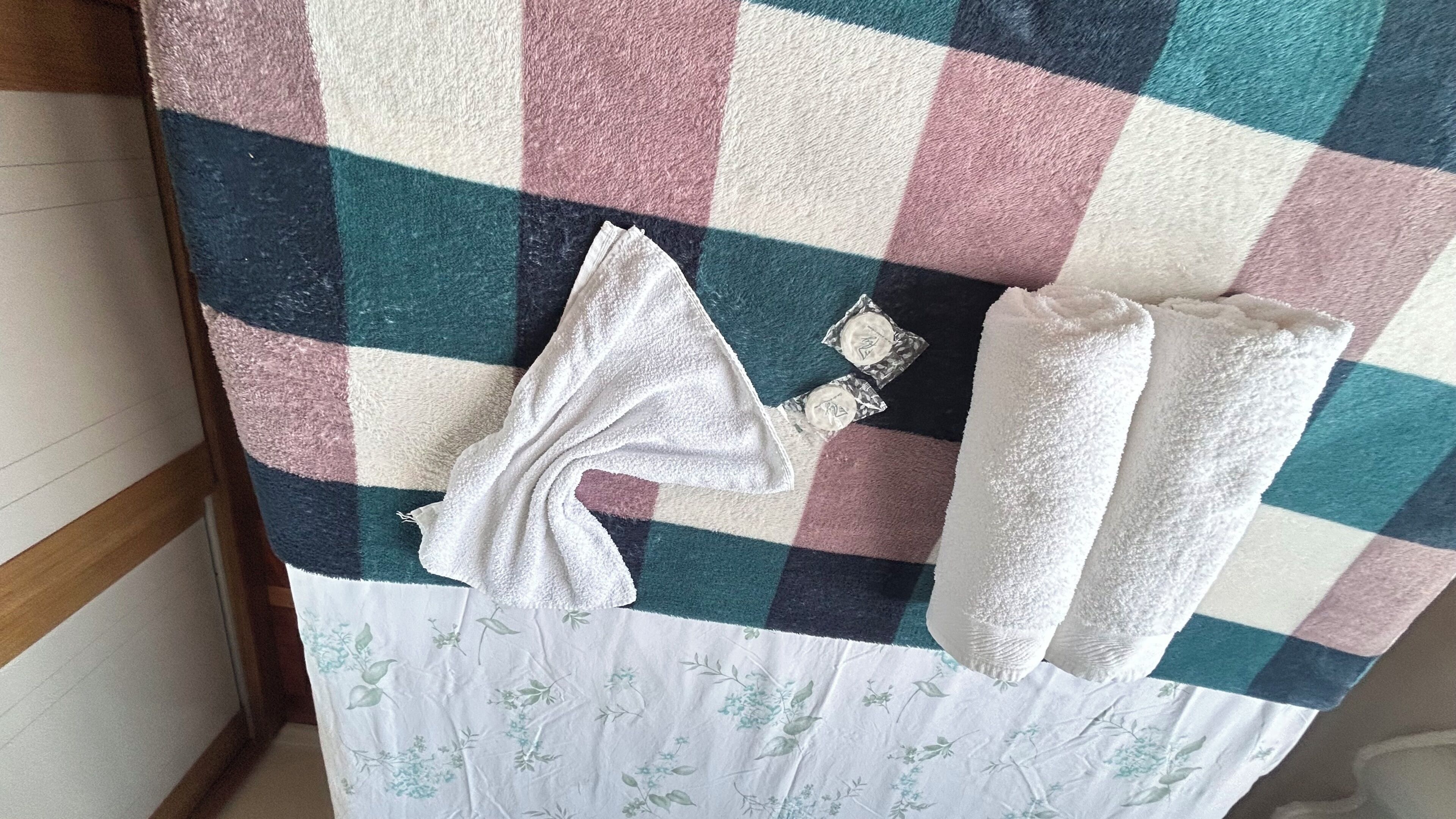 A checkered bedspread with a floral-patterned tablecloth underneath.