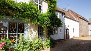 Un bâtiment blanc avec une allée gravillonnée, une porte et une fenêtre.