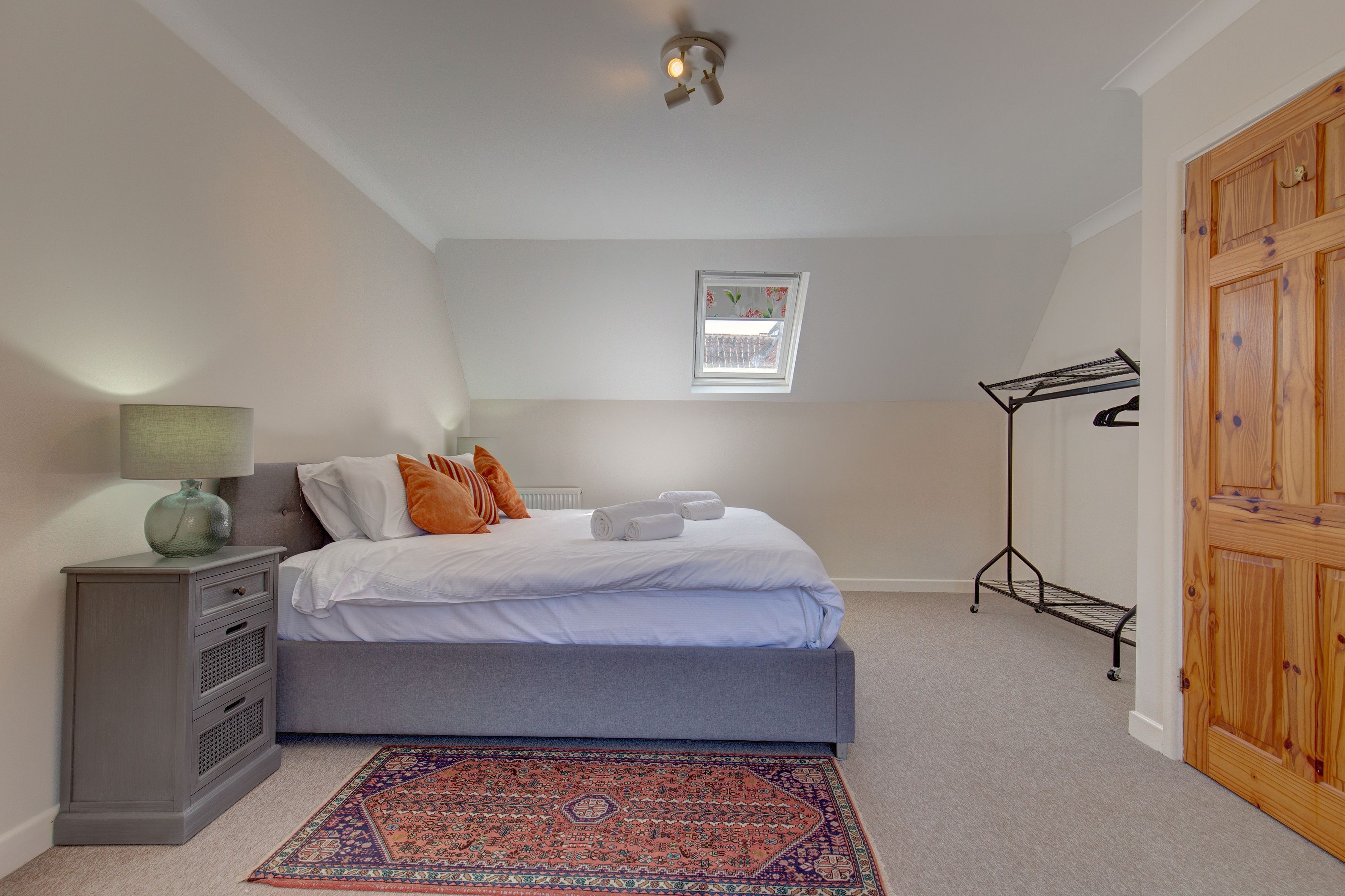 A bedroom with a bed, a nightstand, a window, a ceiling fan, and a wooden wardrobe.