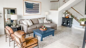 Ein Wohnzimmer mit einer Couch, einem Couchtisch und Ledersesseln. Im Hintergrund ist eine Treppe zu sehen.