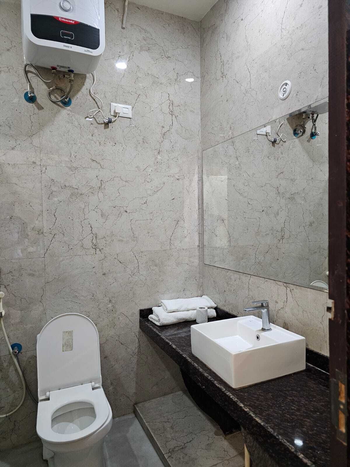 Ein Badezimmer mit Toilette, Waschbecken, Spiegel und Warmwasserbereiter.