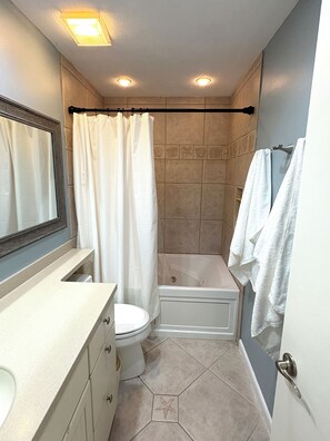 Ein Badezimmer mit Badewanne, Toilette, Waschtisch und Duschvorhang.