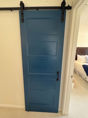 A blue sliding door with a handle, leading to a bedroom with a bed and a nightstand. - Spacious 3-bedroom townhome in Ocean Gallery in St. Augustine steps to pool (St. Augustine)