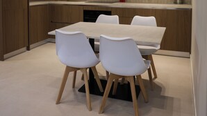 Une cuisine moderne avec un coin repas, des meubles en bois, une table blanche et des chaises.